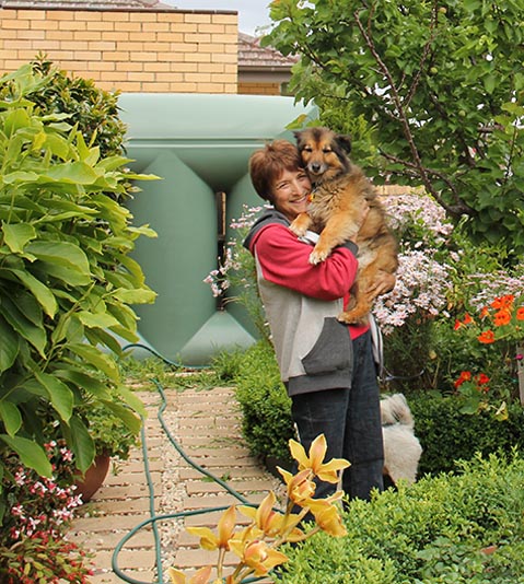 Woman holding her dog in her garden